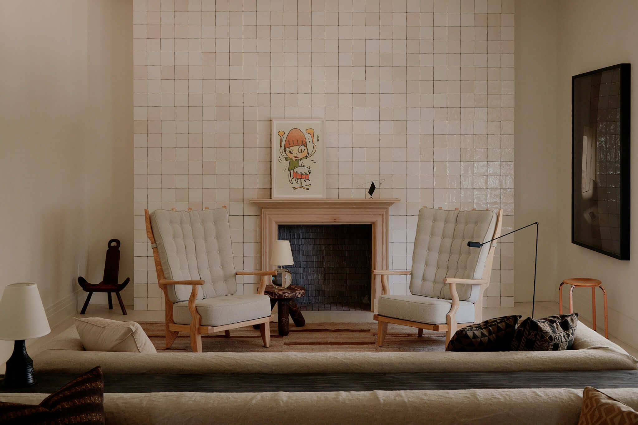 The James Bradley, North America — Mid-century modern living room with cream upholstered chairs, linear fireplace, white subway tile wall, and curated artwork.