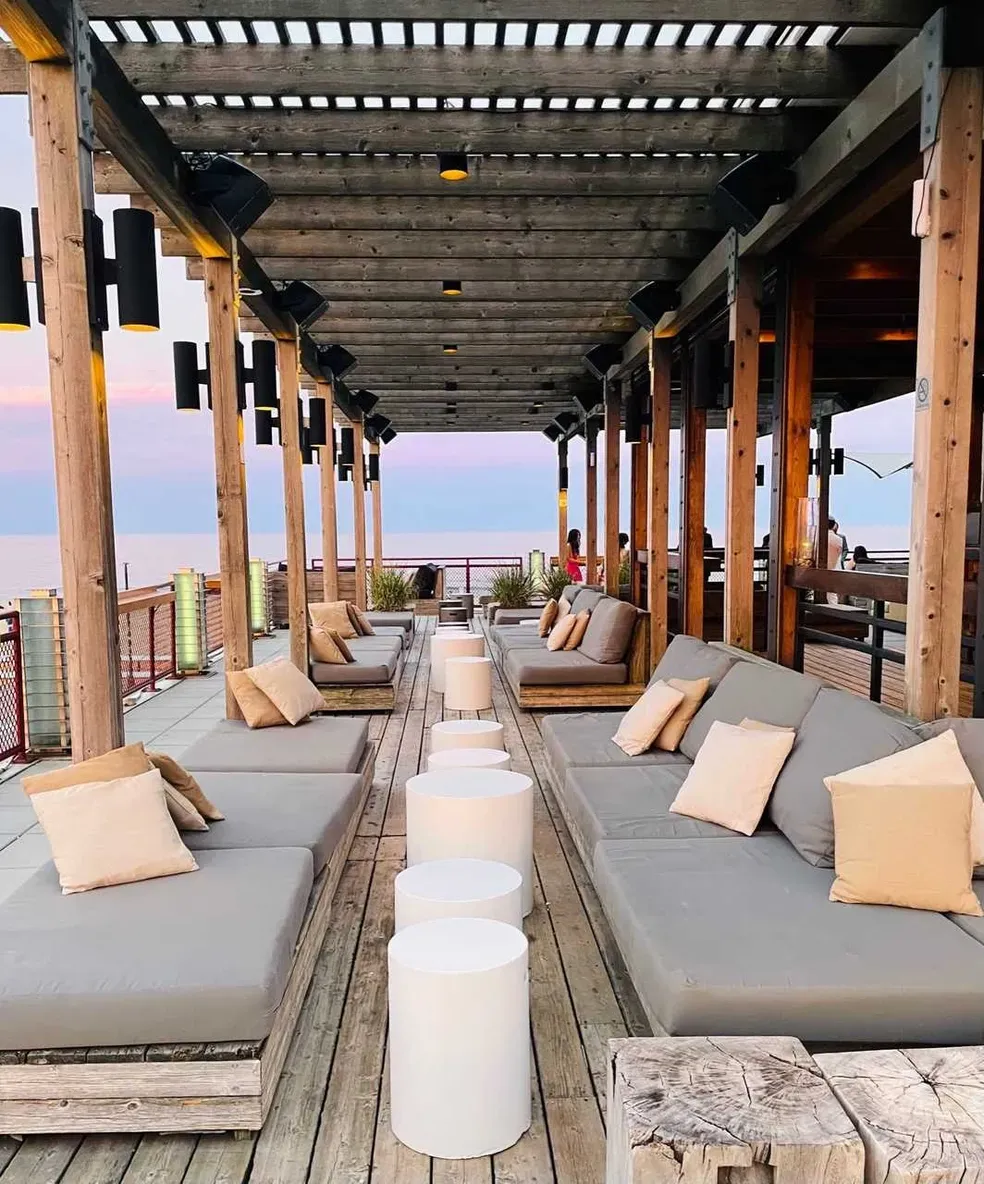 Watermark's covered rooftop lounge at dusk, with recessed daybeds, linen pillows, and sightlines to water beyond timber posts.