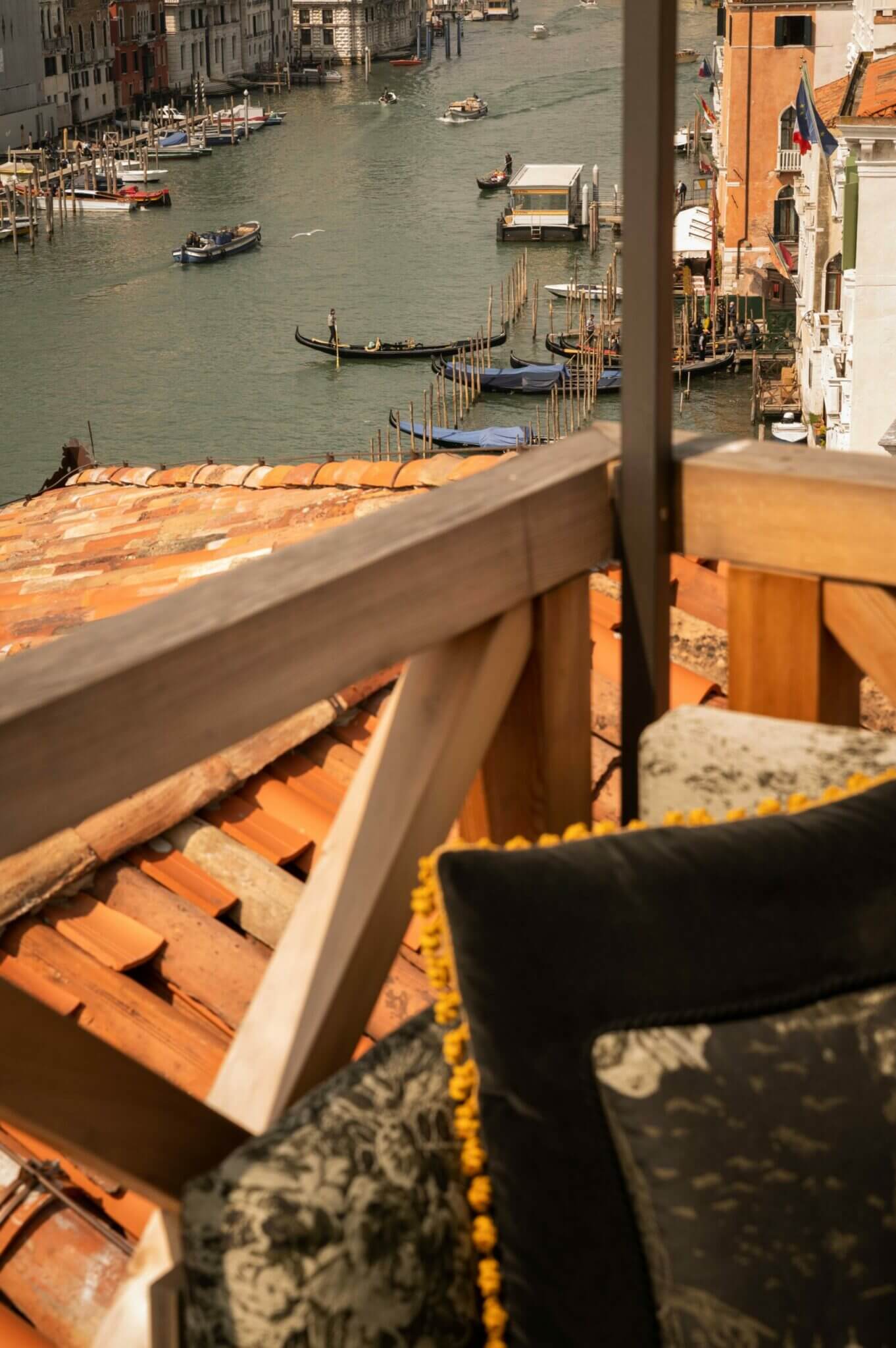 The Venice Venice Hotel, Venice, Italy — Terracotta roof tiles and mooring ropes frame a view of the Grand Canal with gondolas and traditional Venetian architecture.