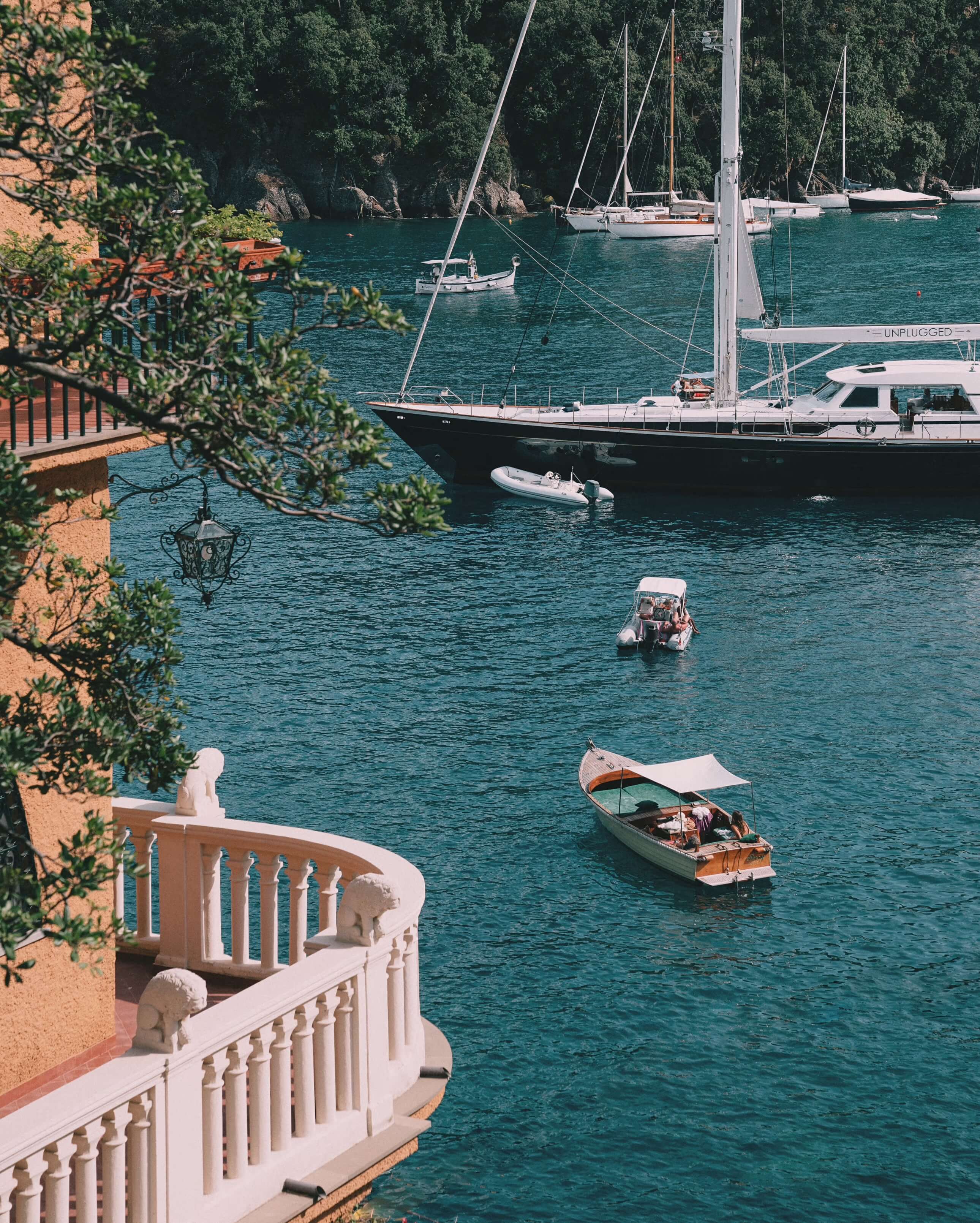 Splendido Mare, Europe — Turquoise cove with moored sailboats and wooden fishing boat, terracotta balustrade and Mediterranean architecture in foreground.