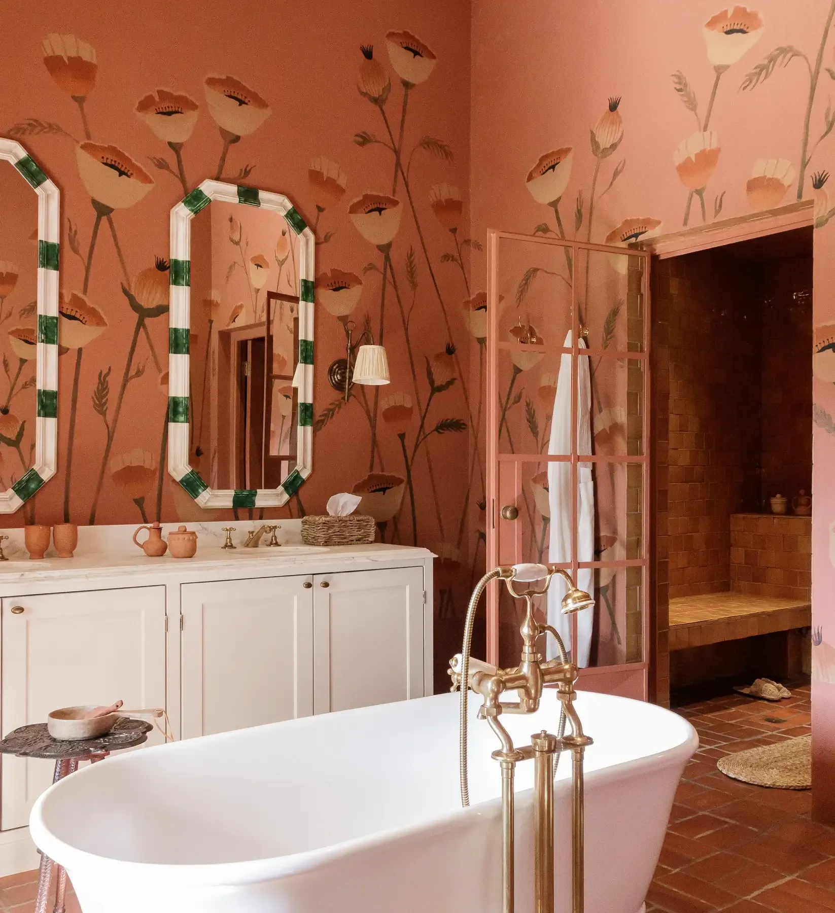 A terracotta bathroom at Sterrekopje features hand-painted botanical walls, a freestanding soaking tub, and brass fixtures.