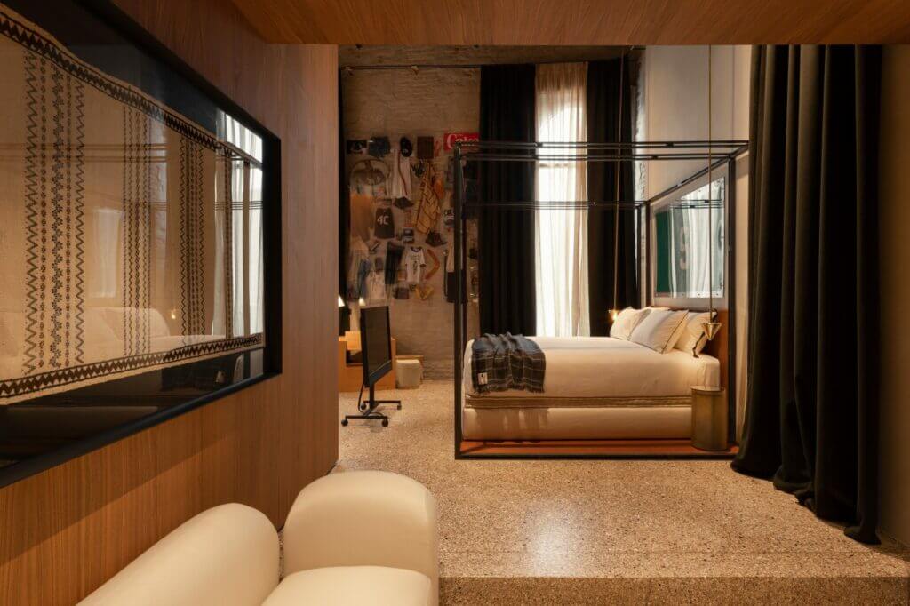 The Venice Venice Hotel, Europe — Luxury suite with canopy bed, warm wood paneling, natural light, modern furnishings, and contemporary interior design.