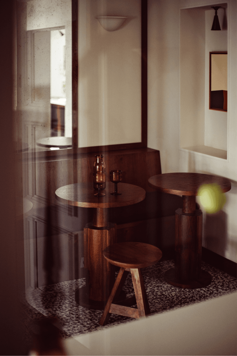 Académies et des Arts, Europe — Intimate lounge with dark wood round tables, terrazzo flooring, cream walls, and warm natural light from transom windows.