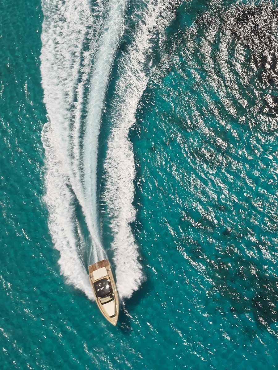 Boat Trip — Speedboat cutting through turquoise Mediterranean waters, aerial view of luxury yacht experience in Balearic Islands with white wake trails.