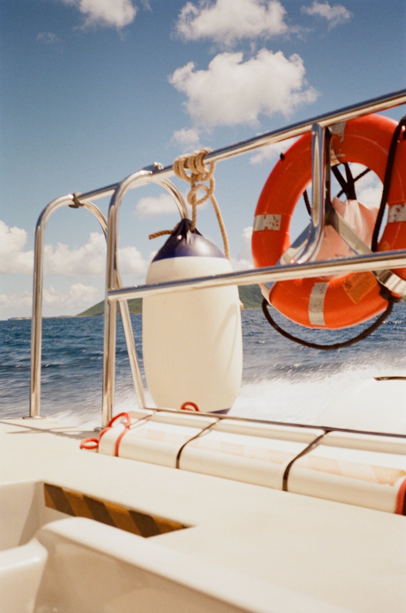 Cap Juluca, North America — Coastal boat deck with cream railings, navy buoy, bright orange life rings, and turquoise Caribbean waters under blue sky.