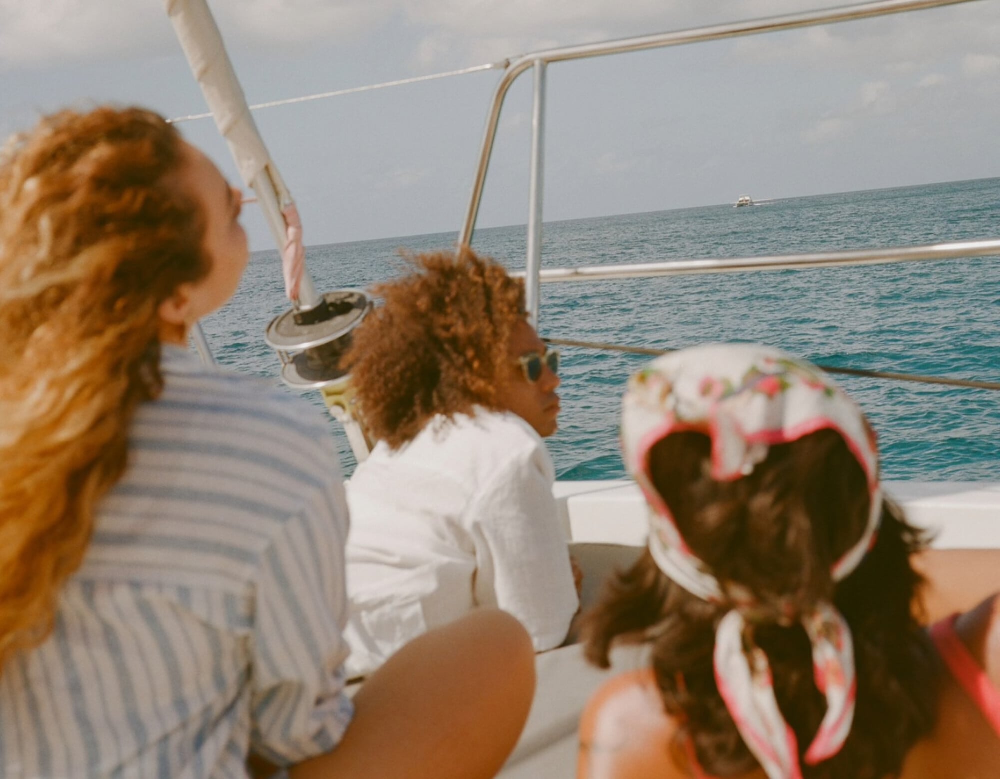 Sail to Prickly Pear Cays, North America — guests with reddish hair on luxury catamaran deck overlooking turquoise Caribbean waters under bright daylight