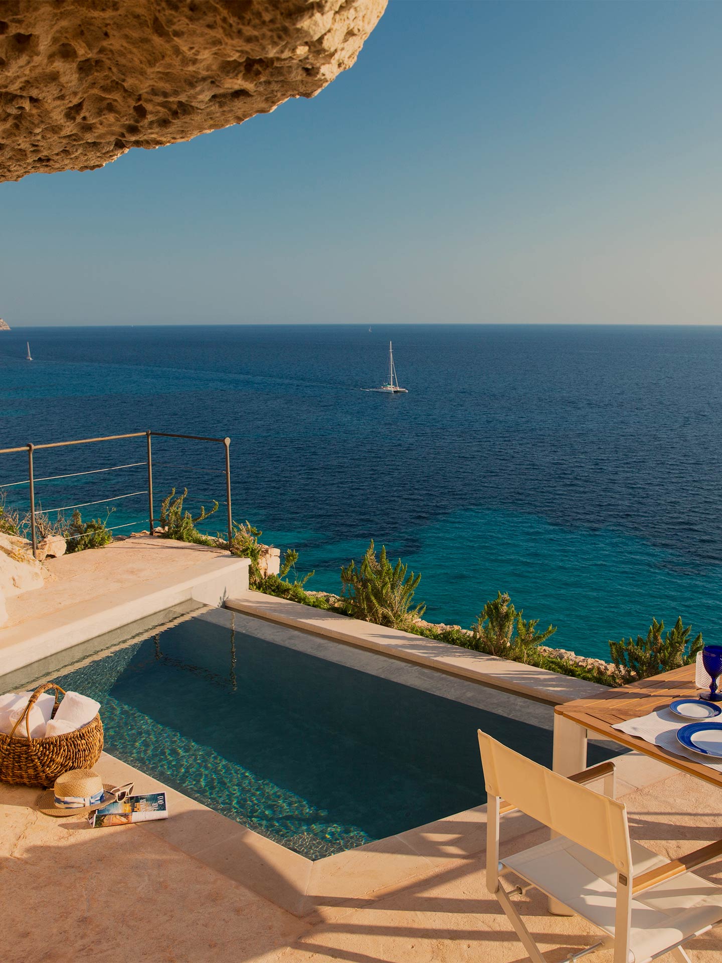 Cap Rocat, Balearic Islands — Infinity pool overlooking Mediterranean Sea with sailboats, limestone terrace, and modern minimalist design.