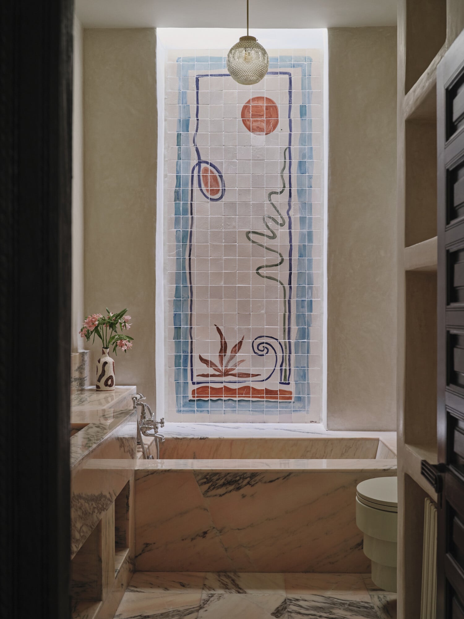 Rosemary, Africa — Marble bathtub with art deco tilework window, pendant brass fixture, minimalist bathroom with sculptural design details.