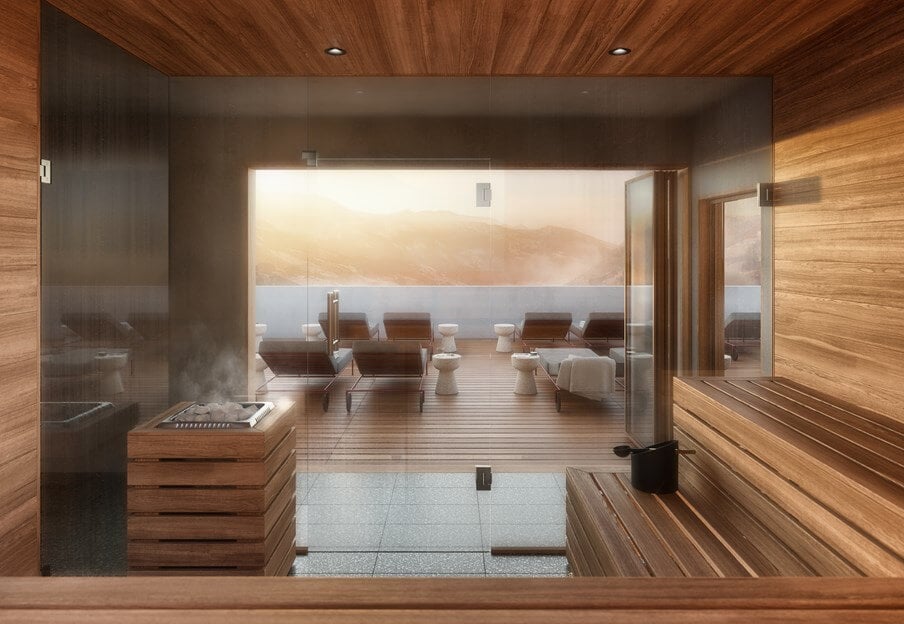 the cōmodo spa — Cōmodo Spa, Europe — Modern sauna with warm wood interiors, glass partition, and panoramic mountain view at sunset, luxury wellness design.