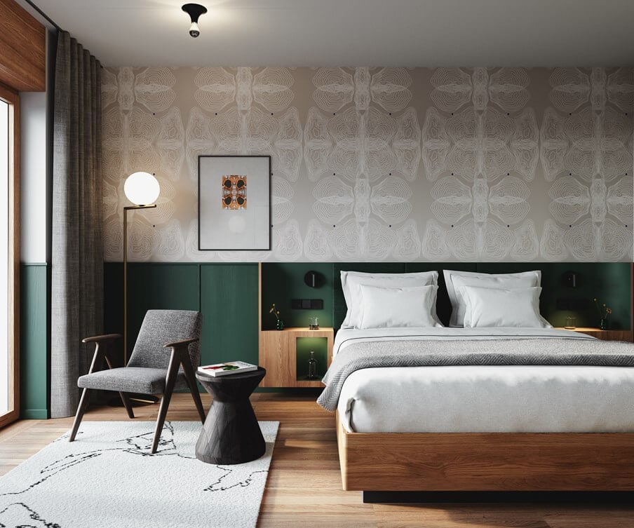 The Cōmodo — Cōmodo, Europe — Modern bedroom with forest-green paneled headwall, geometric wallpaper, mid-century lounge chair, and natural wood furnishings under soft pendant lighting.