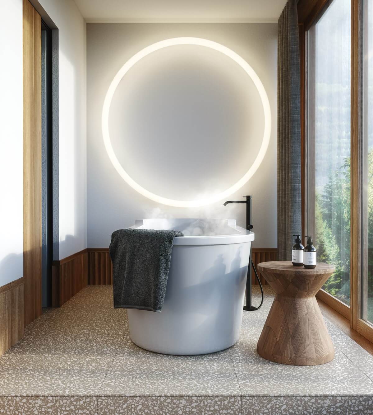 The Cōmodo — Cōmodo, Europe — Minimalist spa bathroom with illuminated circular mirror, cylindrical white soaking tub, wooden side table, and floor-to-ceiling windows overlooking forest landscape.