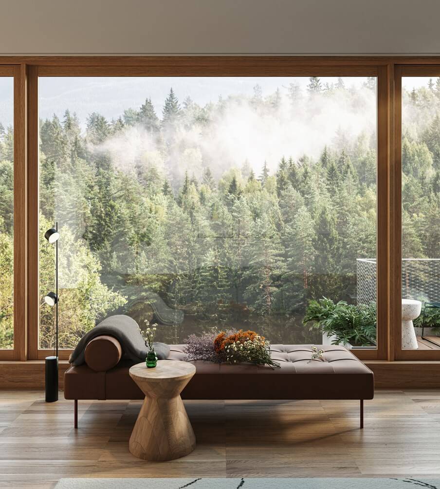 The Cōmodo — Cōmodo, Europe — Modern lounge with dark leather daybed, wooden pedestal table, and floor-to-ceiling windows overlooking misty coniferous forest.