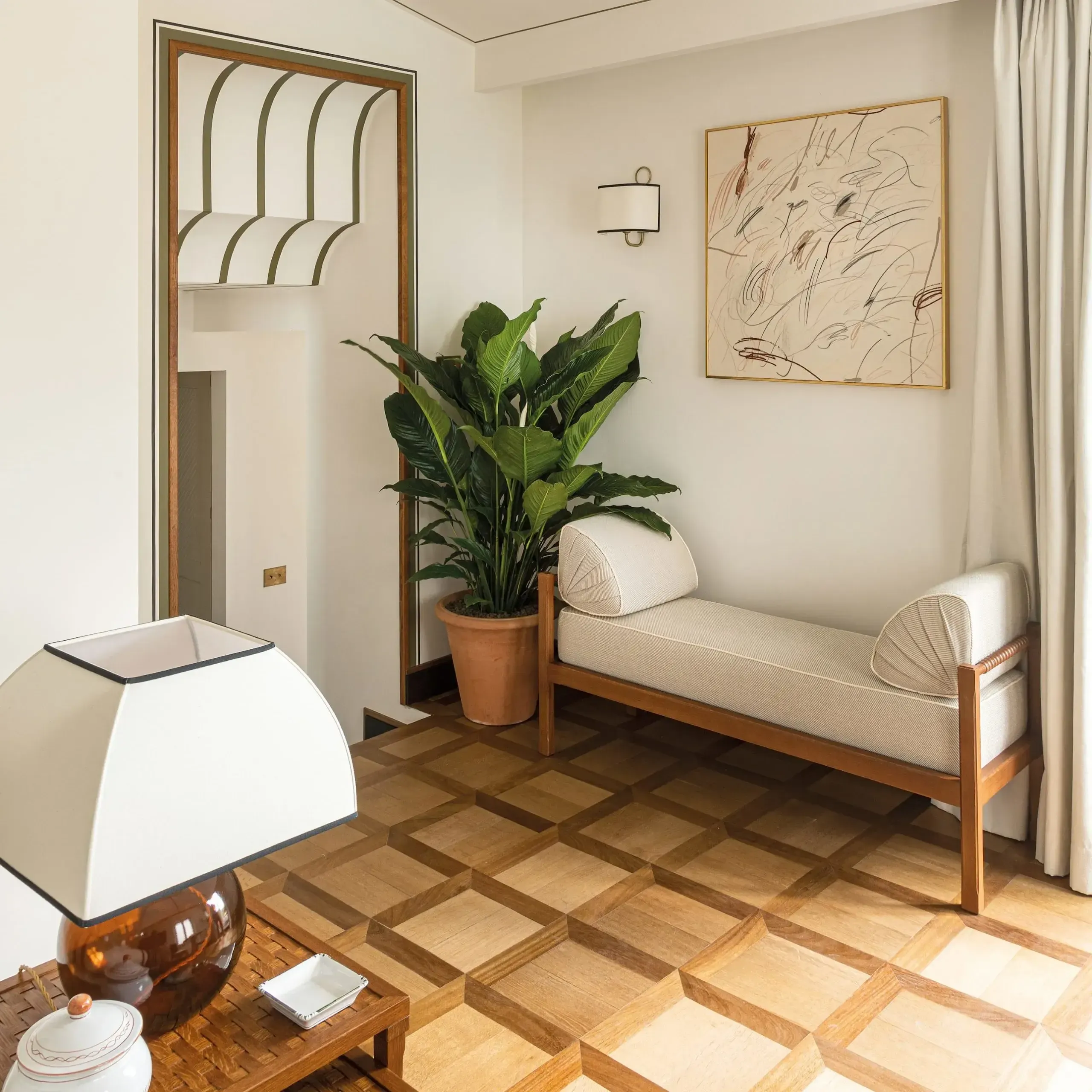Splendido Mare, Europe — Minimalist hotel room with wooden daybed, potted plant, abstract line art, terrazzo flooring, and warm ambient lighting.