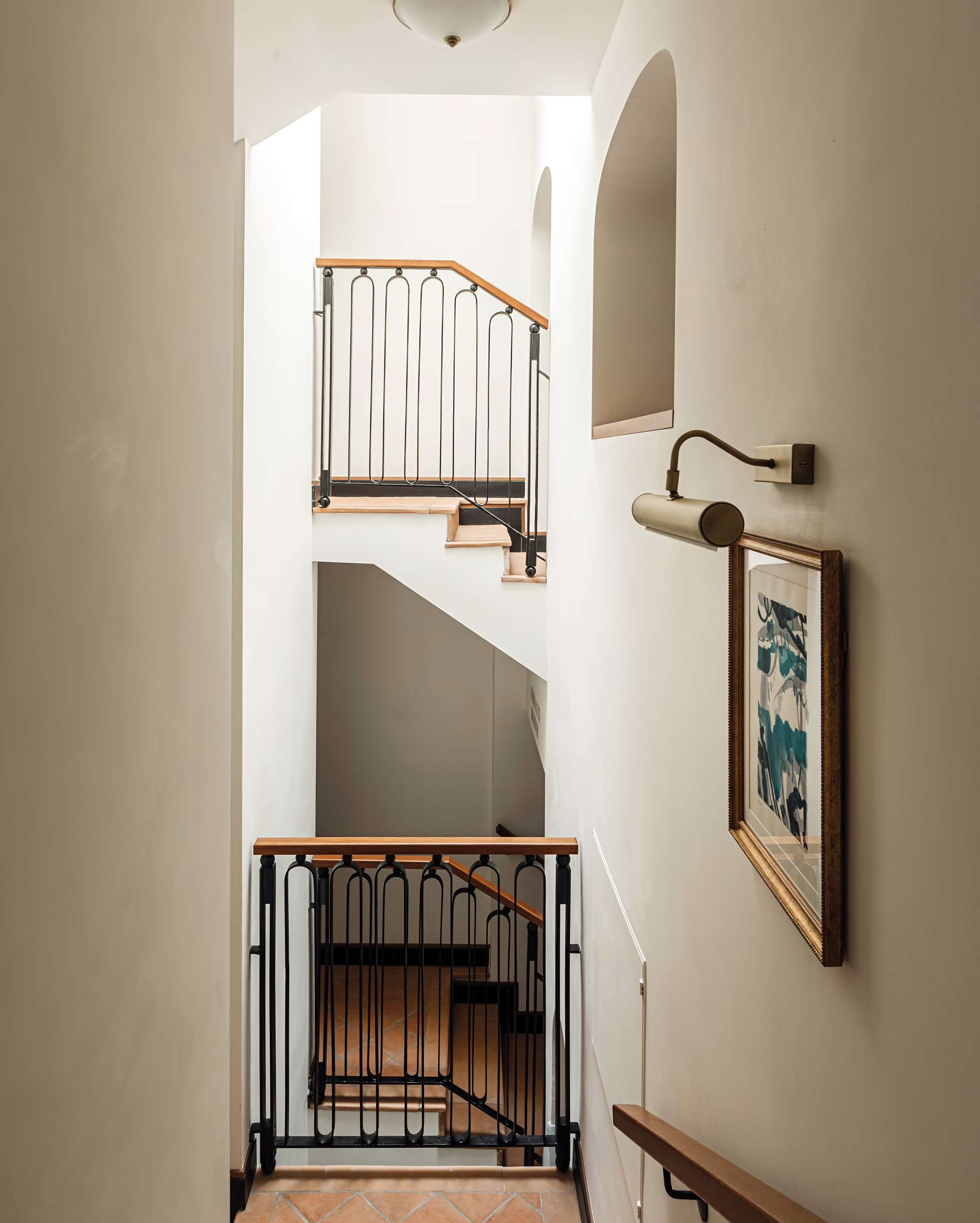 Splendido Mare, Europe — Minimalist stairwell with metal railings, wooden handrails, arched alcoves, neutral plaster walls, and framed botanical artwork casting soft natural light.