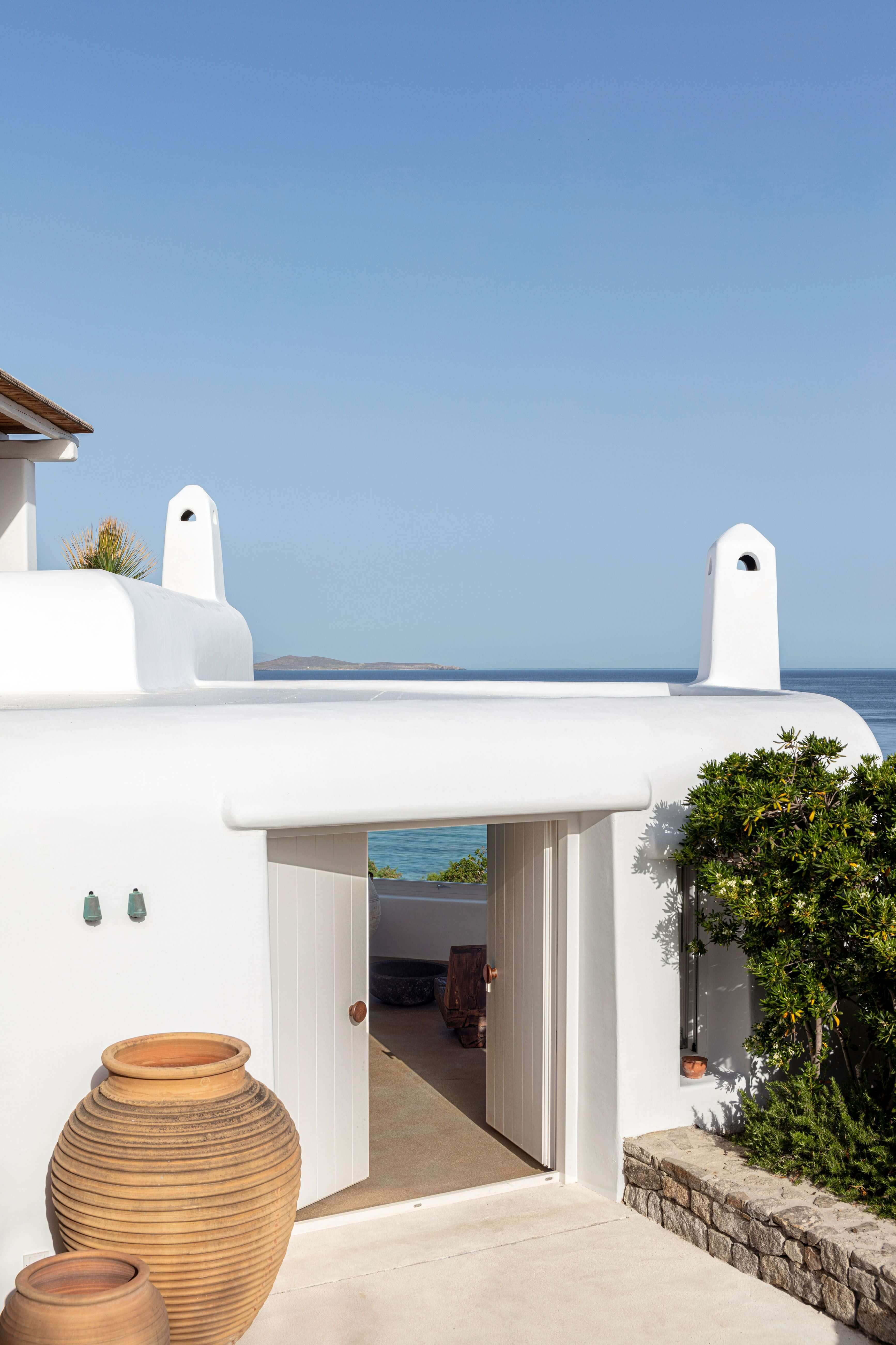 Villa Tama, Europe — Whitewashed Cycladic architecture with curved walls, arched chimneys, and sea view terrace overlooking blue Mediterranean waters.