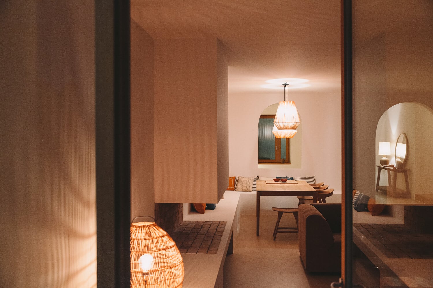 Casa Santa Teresa, Europe — Warm terracotta interiors with pendant lighting, wooden furniture, arched doorways, and minimalist decor creating serene hospitality spaces.