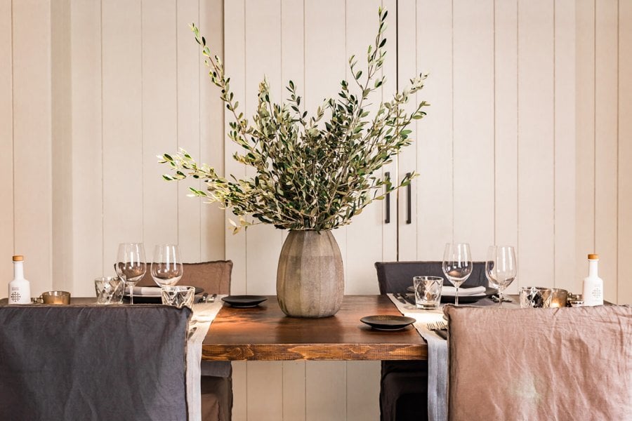 Quadrat Restaurant, Balearic Islands, Spain — Minimalist dining table with dried grasses, wooden surface, linen runners, wine glasses, and neutral palette against shiplap wall.