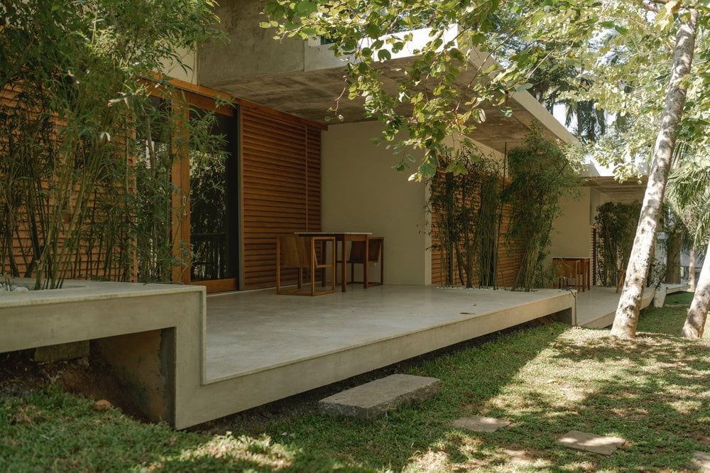 Kurulu Bay, Asia — Modernist villa terrace with concrete platform, timber screens, and birch trees creating dappled shade over minimalist seating area.
