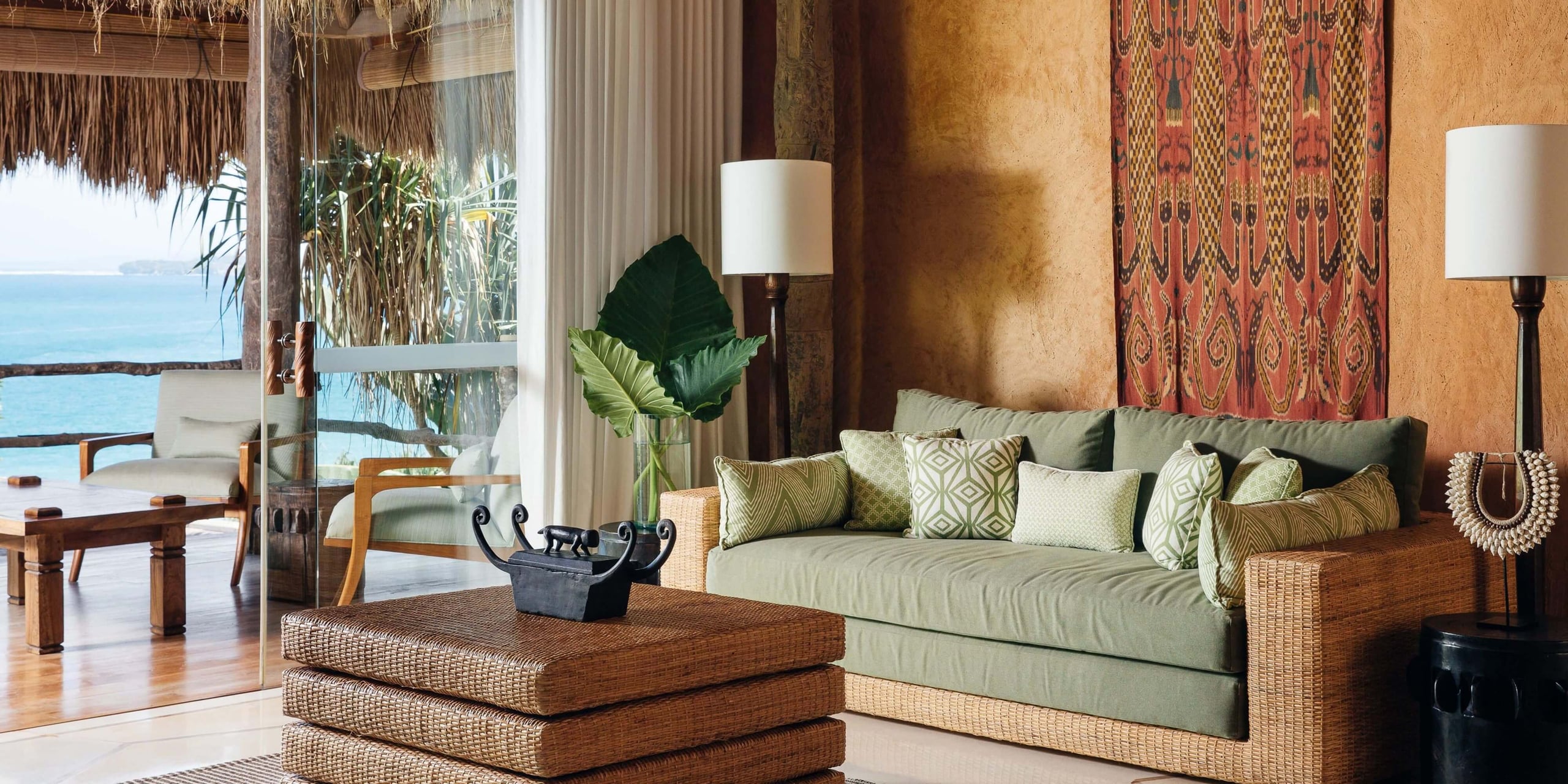 NIHI Sumba, Indonesia — Coastal resort living room with woven furniture, sage upholstery, ocean views, and traditional textile details.