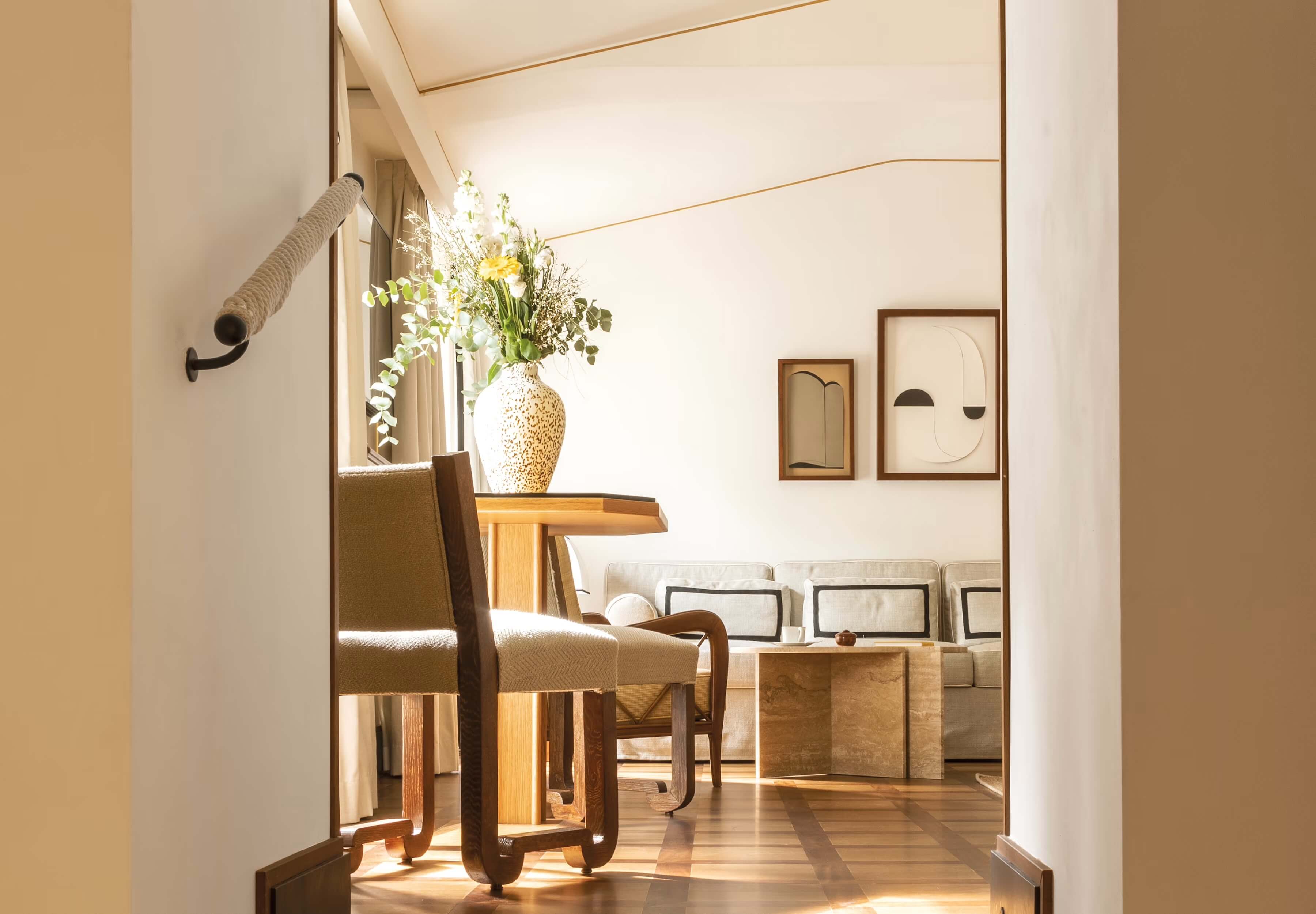 Splendido Mare, Europe — Minimalist hallway with natural light, wooden furniture, textured vase with flowers, and line-art wall prints in neutral tones.