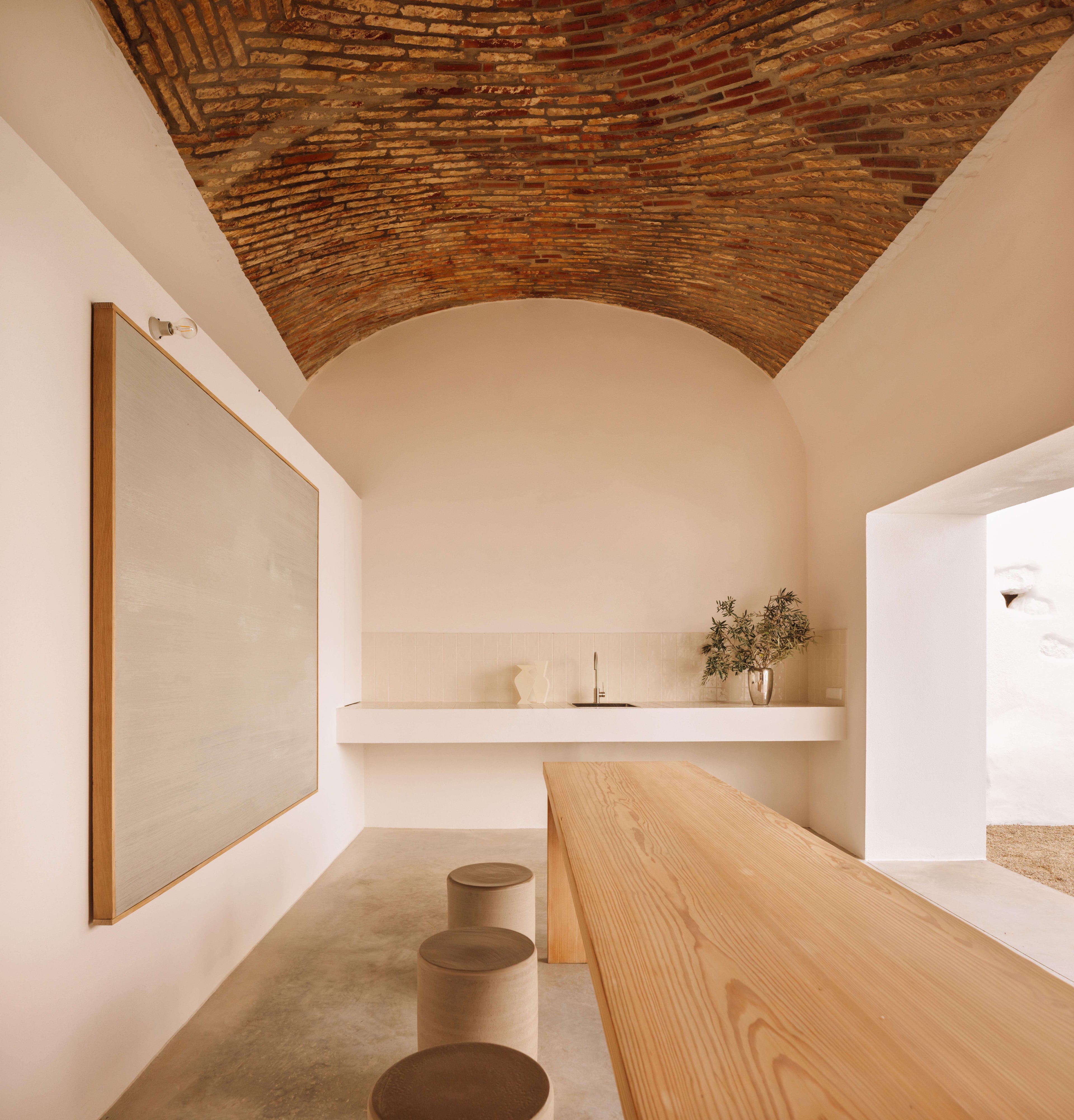 Casa Quatro, Europe — Minimalist spa with barrel-vaulted brick ceiling, wooden bench, white floating shelf, and natural light creating serene wellness interior.