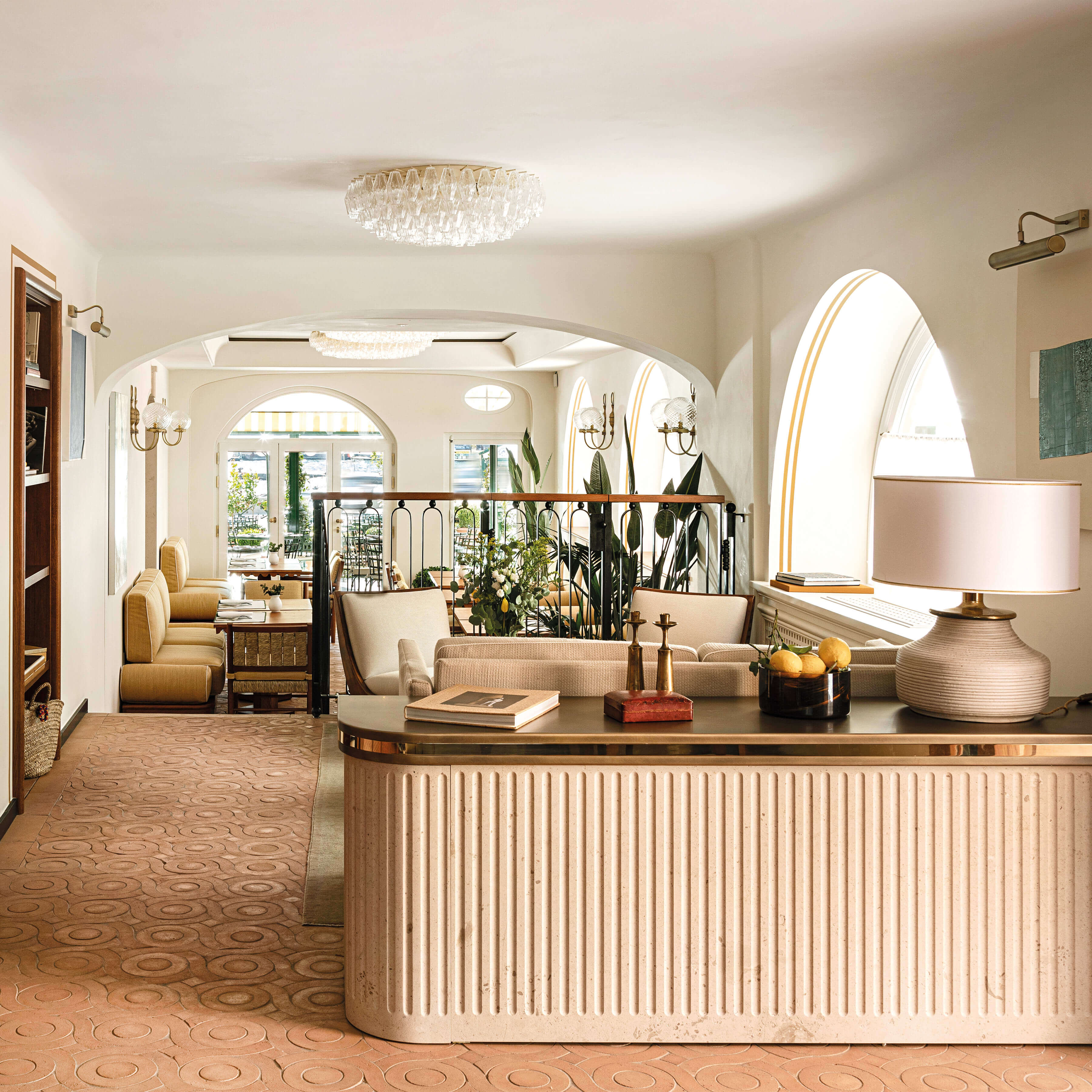 Splendido Mare, Europe — Curved archways frame a luminous lobby with travertine desk, brass fixtures, and seaward-facing arched windows flooding the cream interior with natural light.