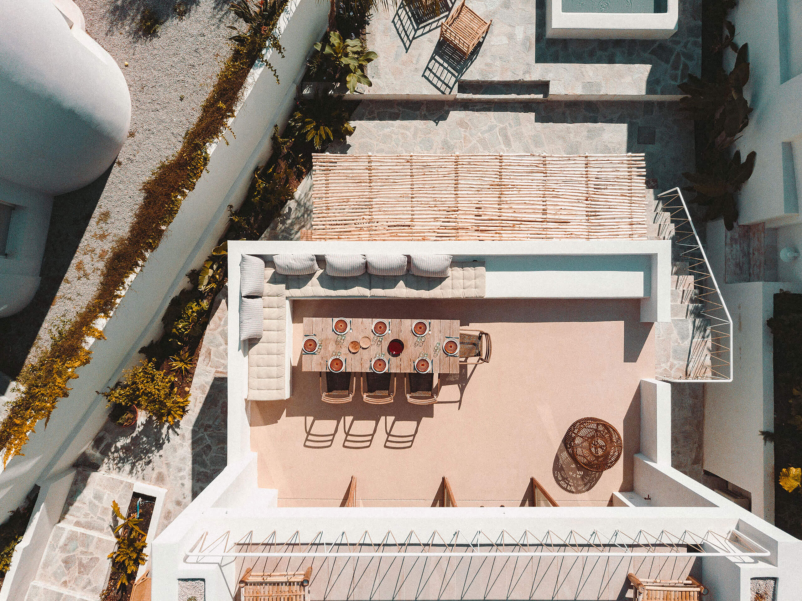 Casa Santa Teresa, Europe — Aerial terracotta terrace with linen loungers, dining table, and Mediterranean architecture casting geometric shadows in bright sunlight.