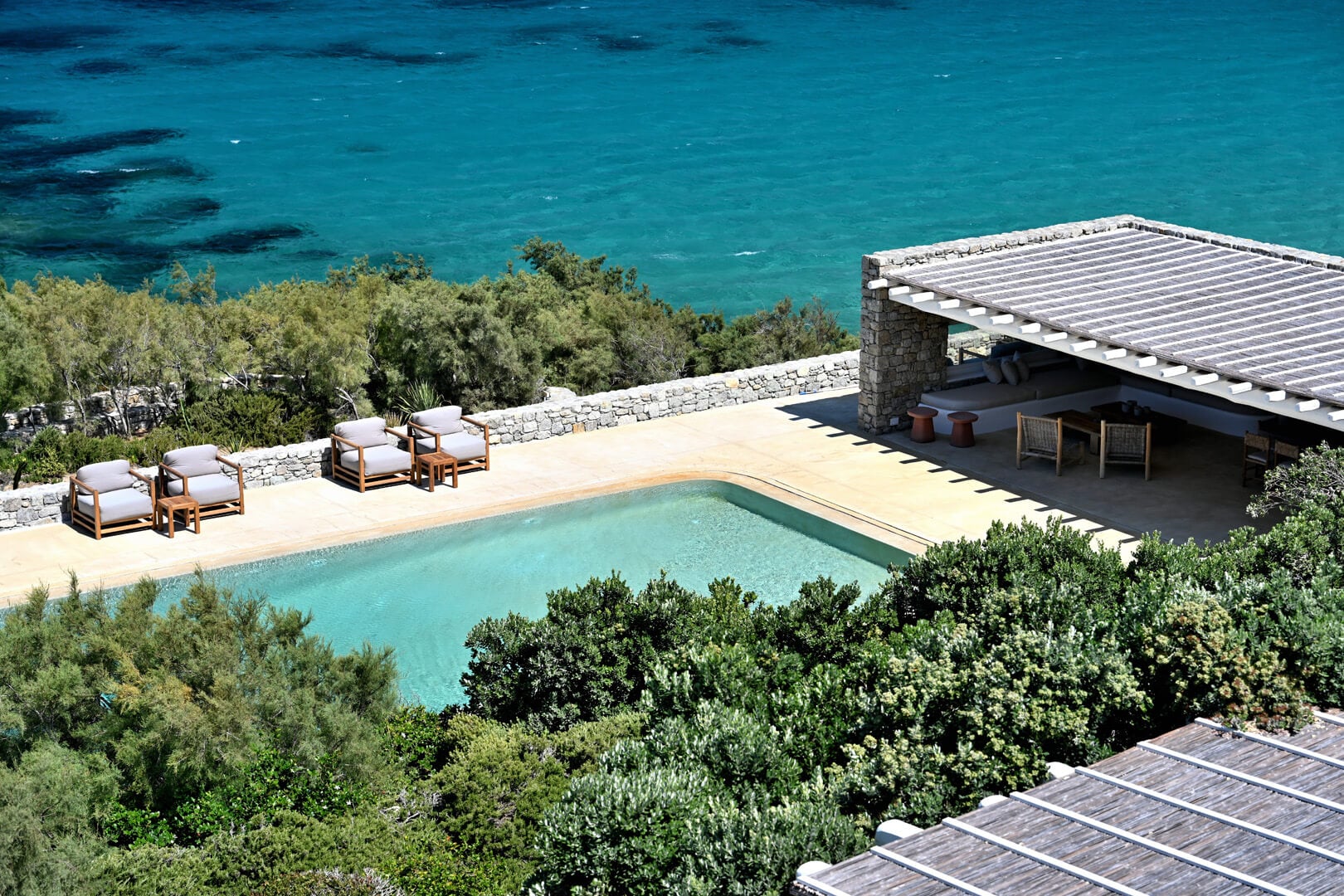 Villa Tama, Europe — Coastal villa with terraced pool, stone architecture, wooden loungers, and turquoise Mediterranean sea views beyond manicured gardens.