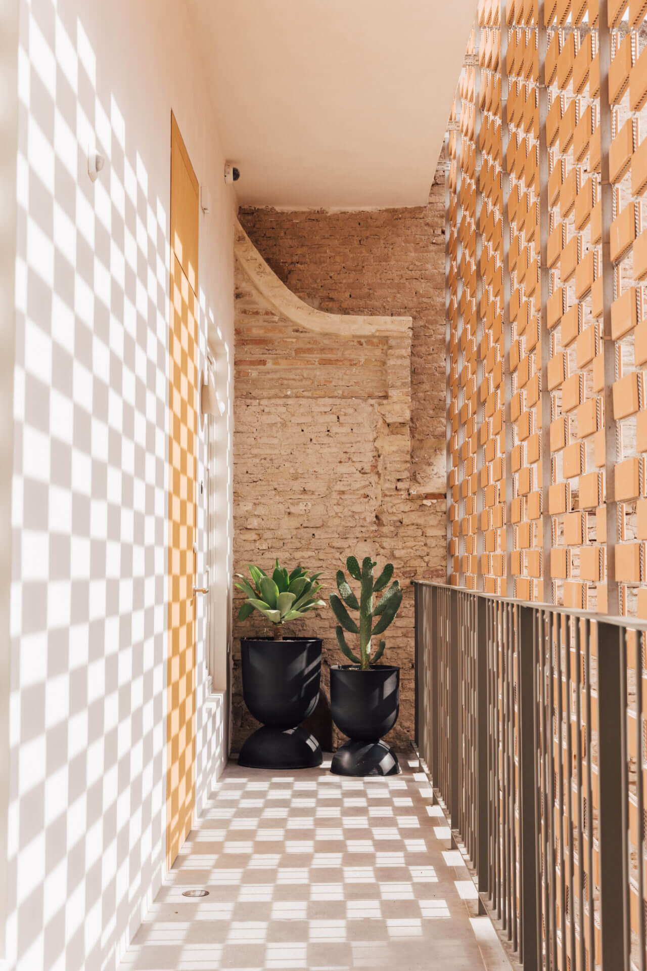 Sunlit corridor with planters at Placido y Grata Hotel