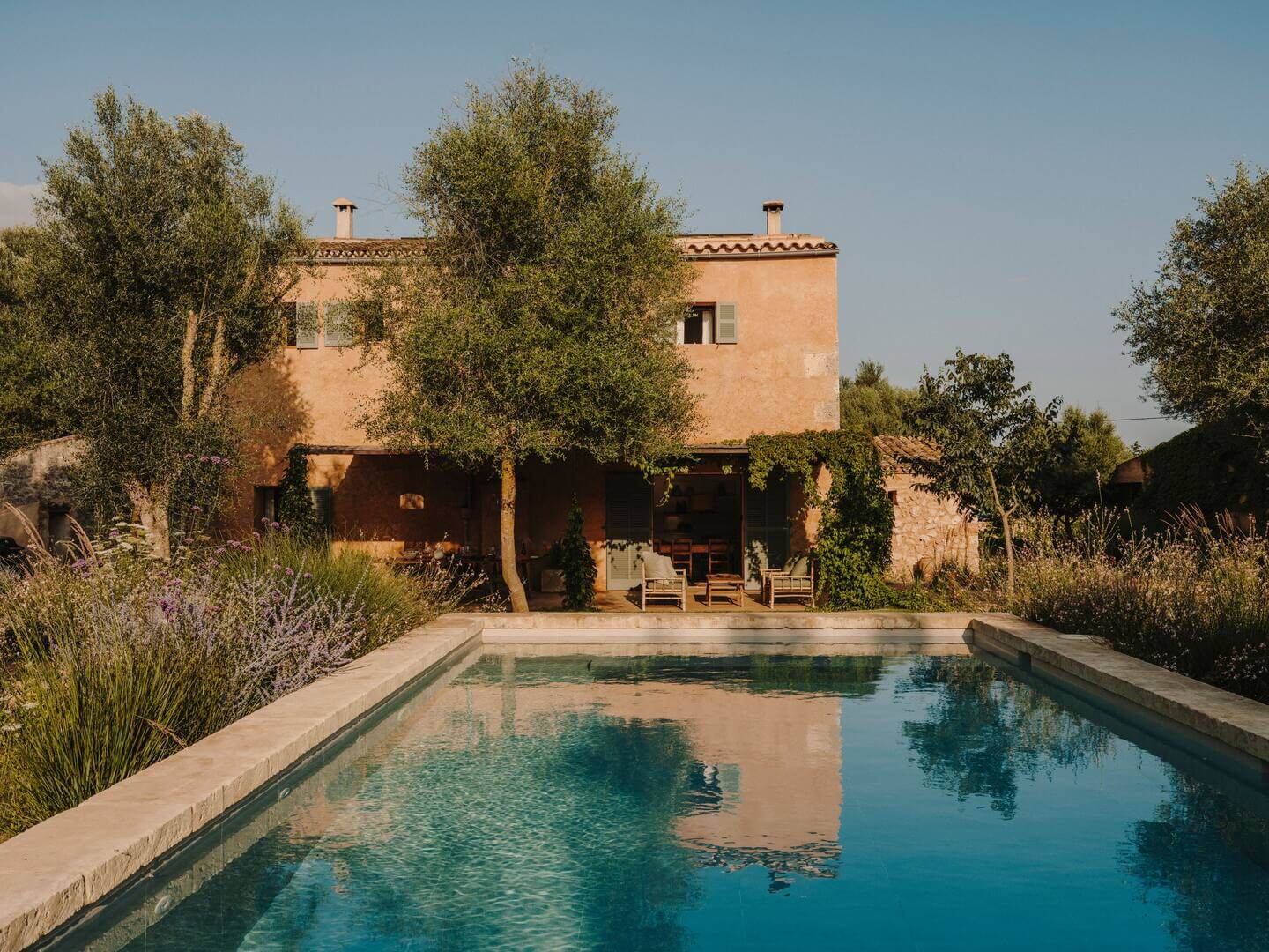 Can Lluïssó, Balearic Islands, Spain — Terracotta villa with swimming pool, olive trees, lavender garden, and covered loggia at golden hour.
