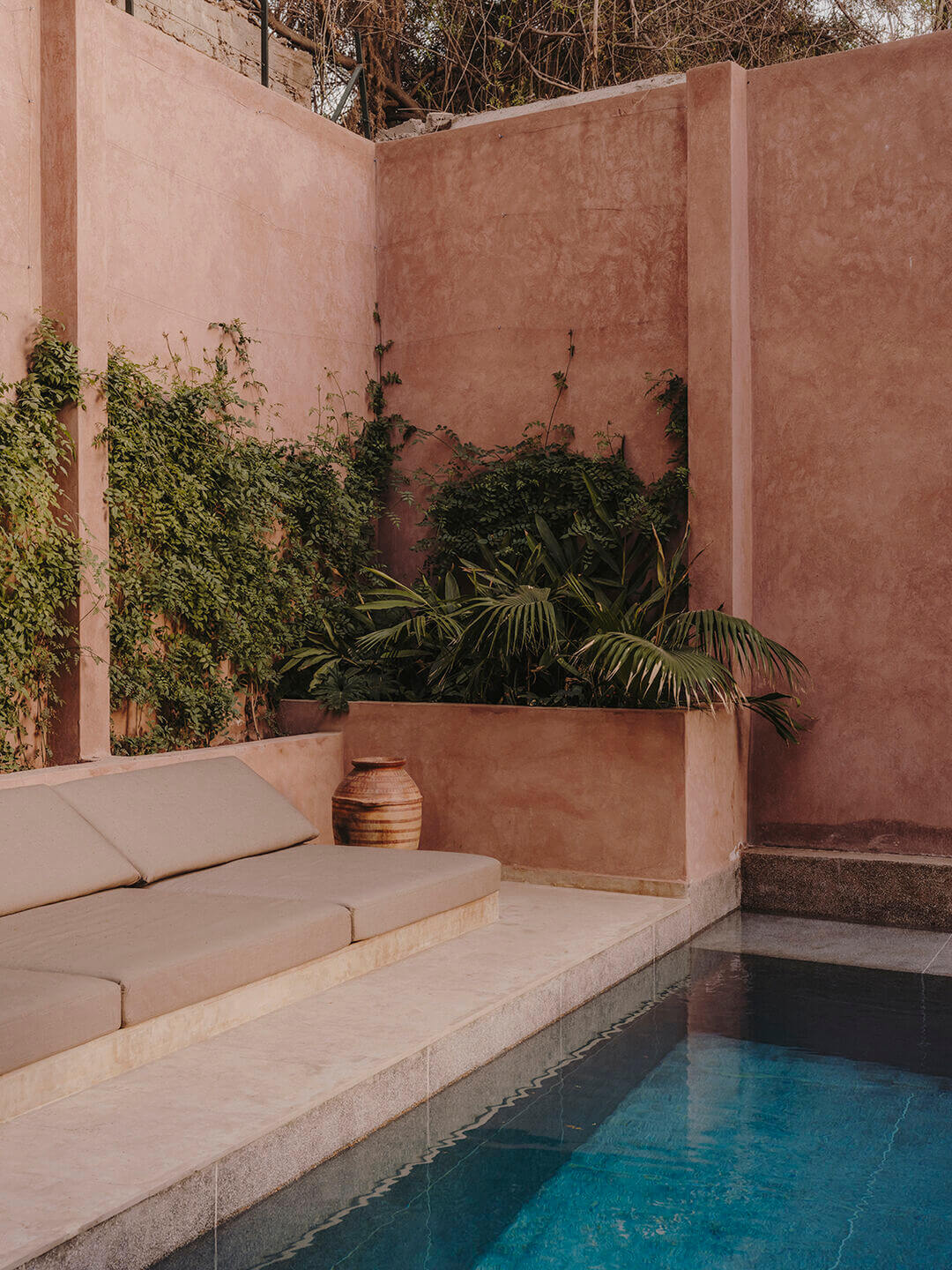 Maison Brummell Majorelle, Africa — Terracotta courtyard with built-in seating, plunge pool, climbing ivy, potted palms, and taupe stucco walls.