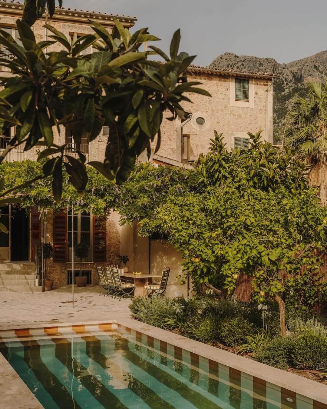 Santa Teresa 34, Balearic Islands, Spain — Ochre stone villa with pool, palm trees, and mountain views in Mediterranean courtyard garden.
