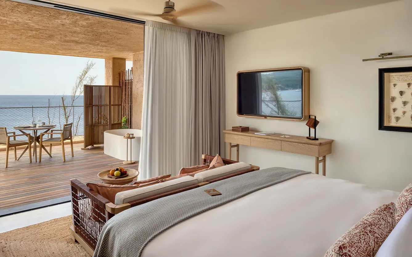 Six Senses Ibiza, Balearic Islands, Spain — Coastal bedroom with wooden furnishings, sea-view terrace, natural light, and minimalist Mediterranean design aesthetic.