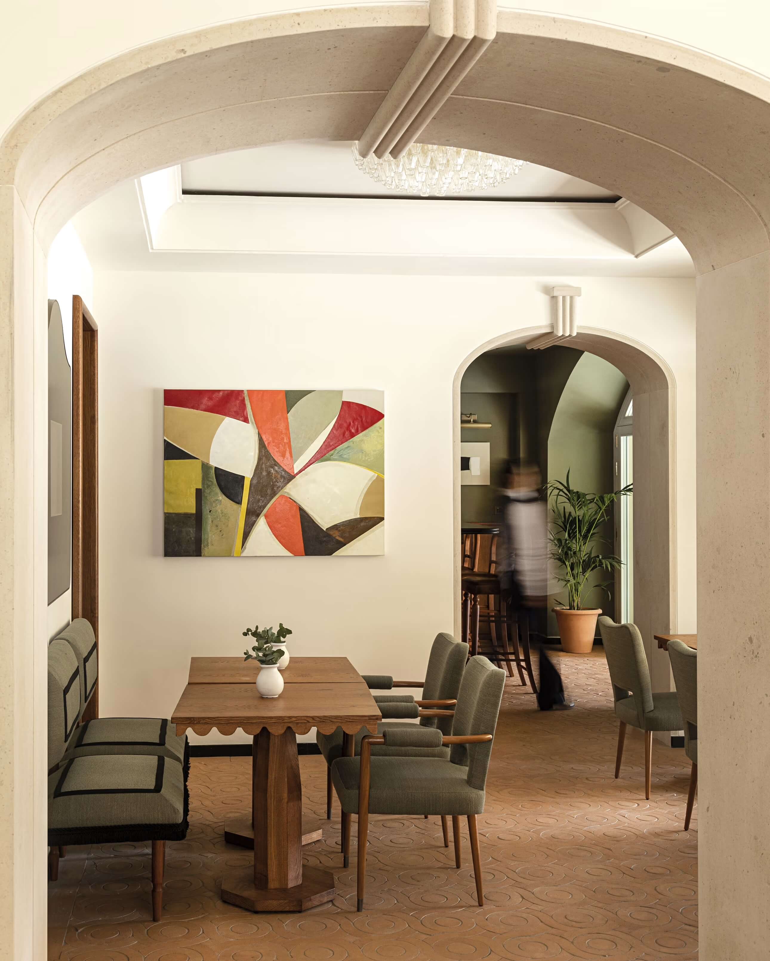 Splendido Mare, Europe — Arched doorway opening to dining room with mid-century chairs, wooden table, abstract artwork, and terracotta flooring.