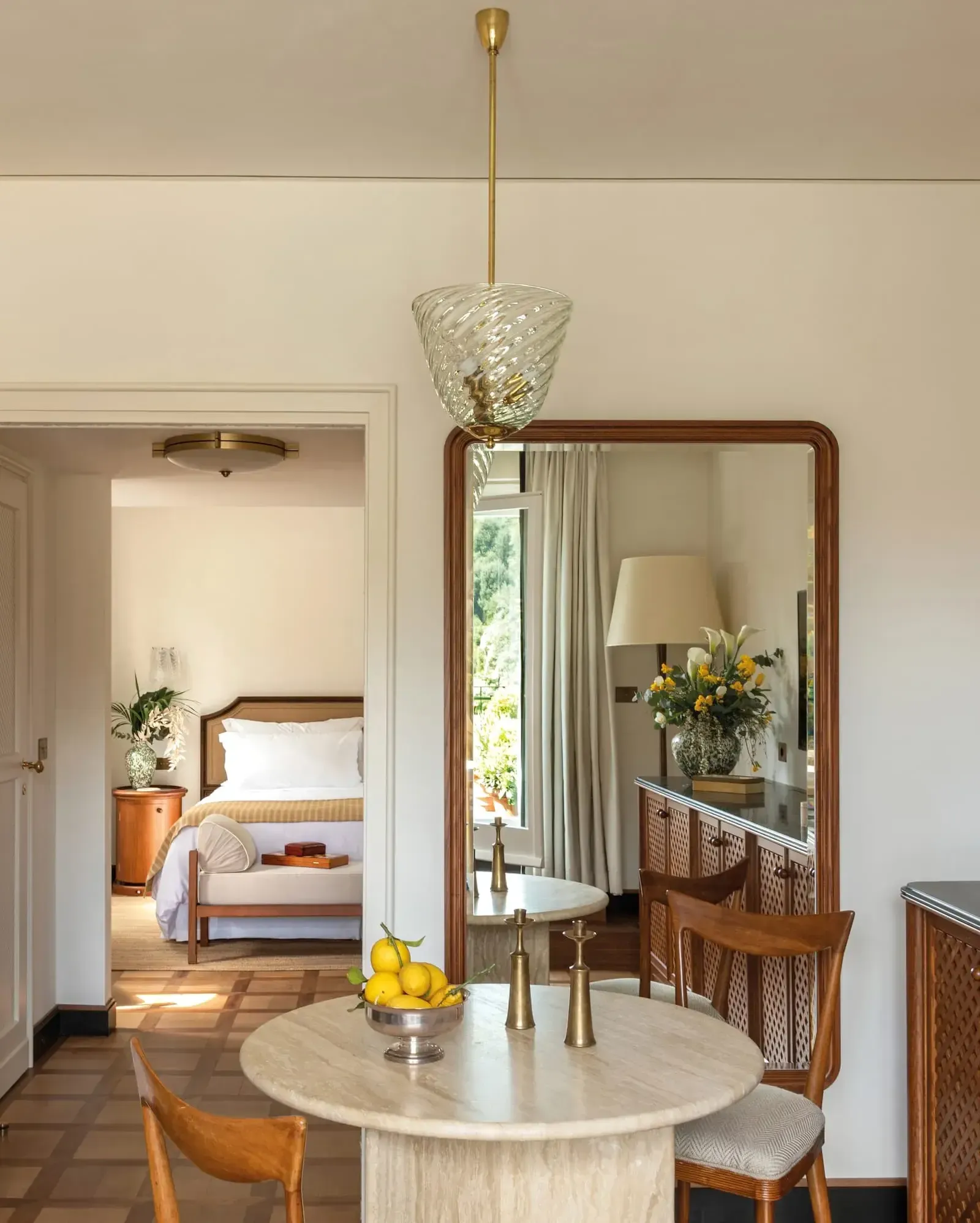 Splendido Mare, Europe — Pendant light above marble round table with leather chairs, large mirror reflecting bedroom doorway and floral arrangement, midcentury modern interiors.