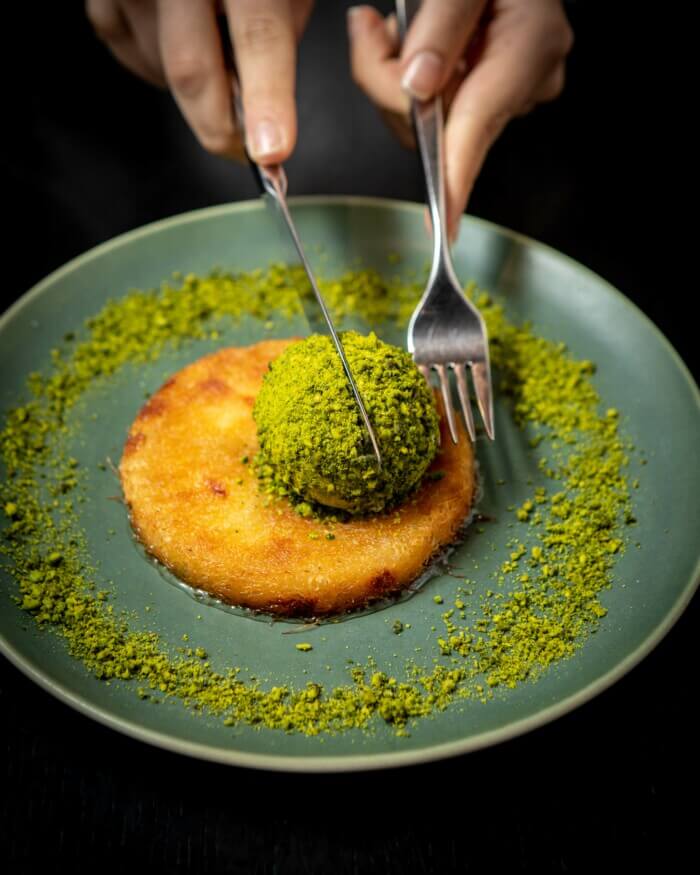 Ruya Restaurant, Europe — Pistachio-dusted dessert with caramelized dome on sage ceramic plate, fine dining plating detail.