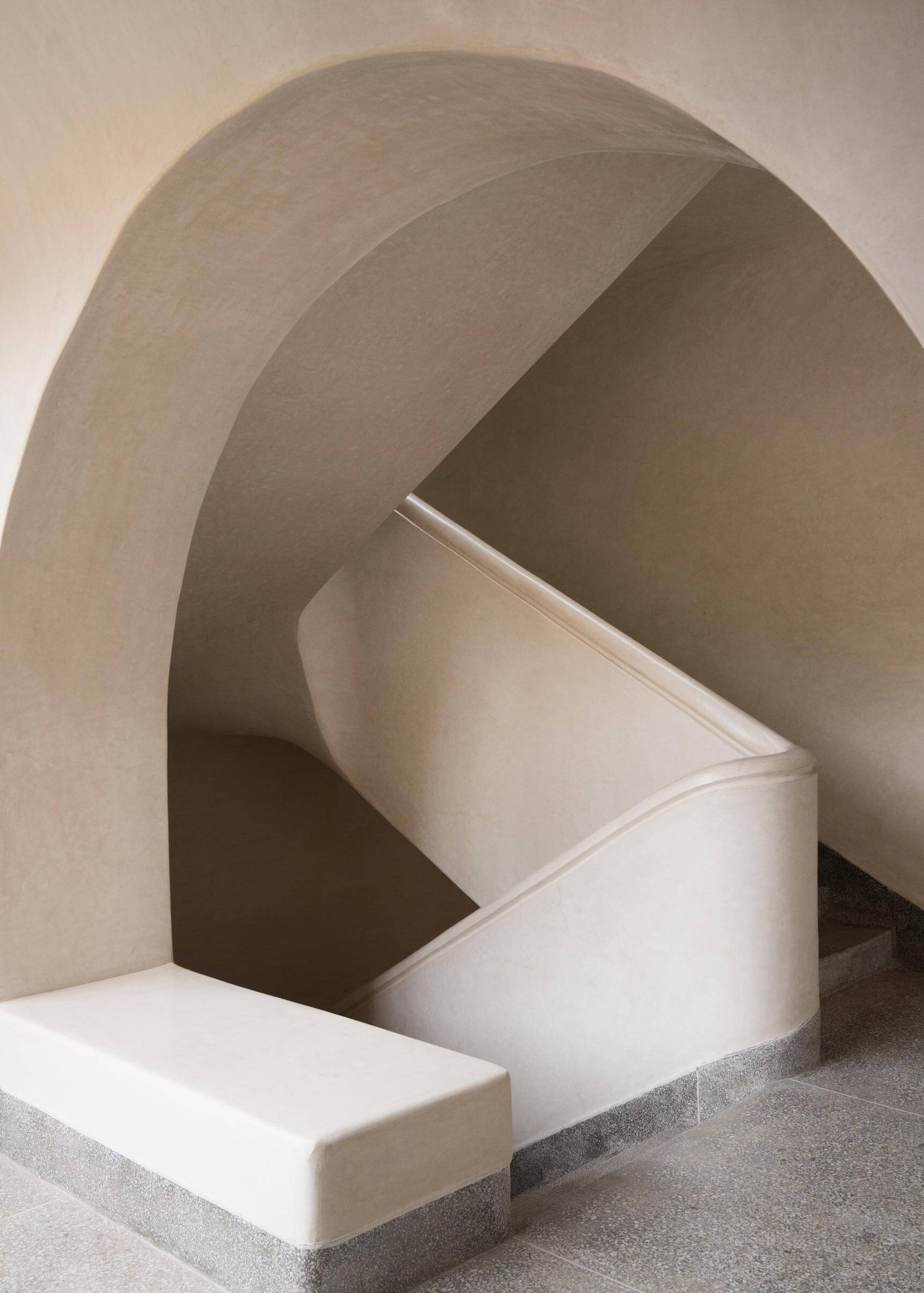 Maison Brummell Majorelle, Africa — Sculptural arched concrete alcove with curved white plaster form and minimalist stepped platform, gallery installation displaying modernist architectural design.