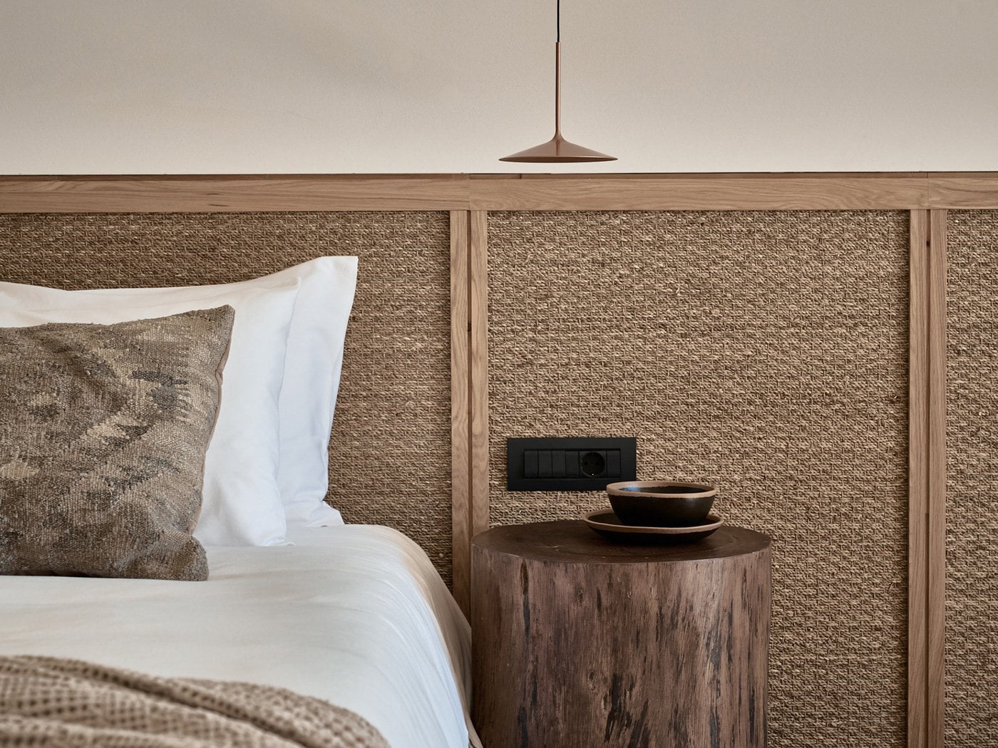 Olea All Suite Hotel, Europe — Modern hotel bedroom with textured headboard, wooden nightstand, ceramic cup, pendant light, neutral palette.