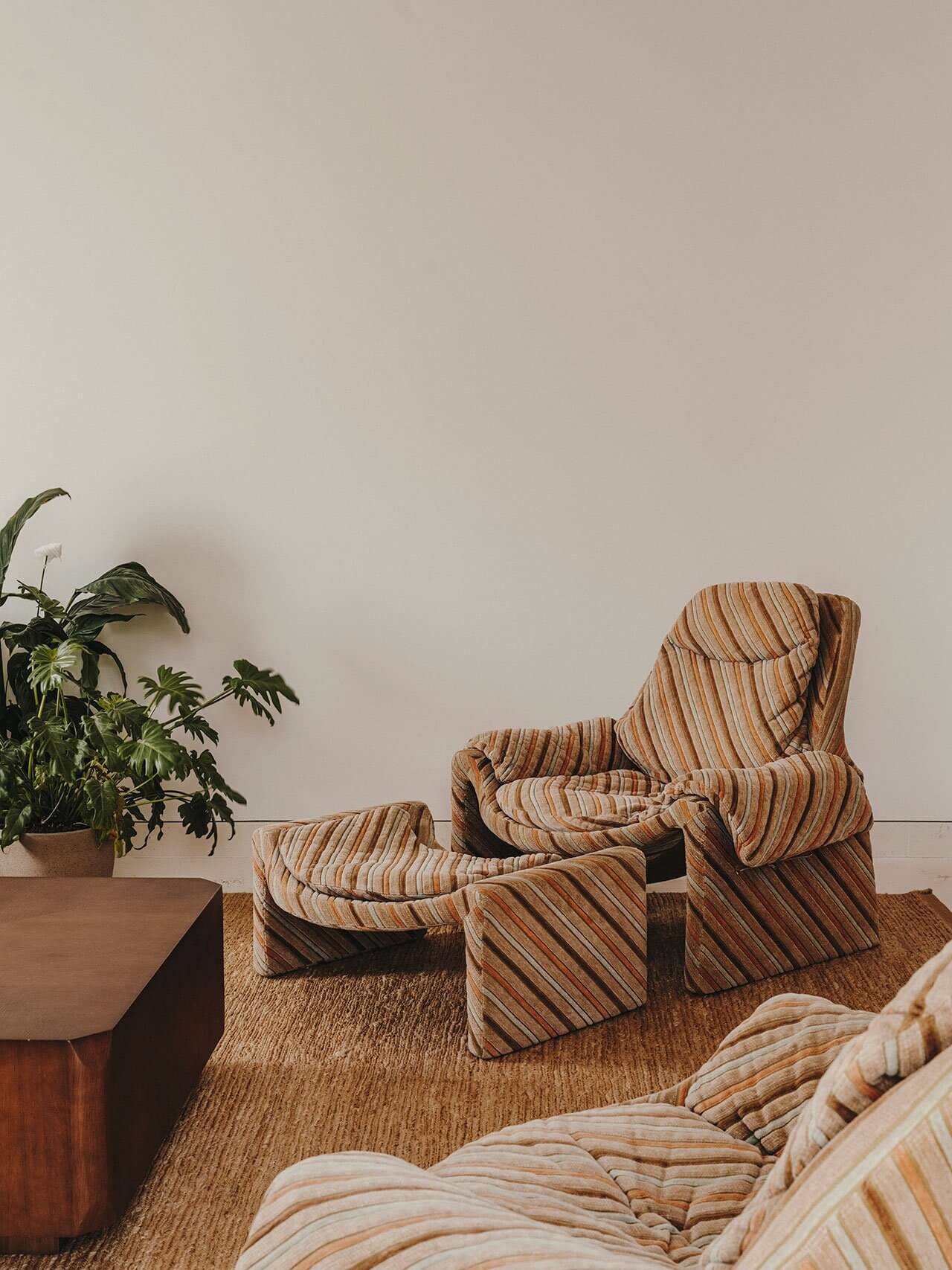 The Standard Ibiza, Balearic Islands, Spain — Striped linen lounge chair and ottoman on natural fiber rug beside wooden side table with potted plant, minimalist hospitality interior design.