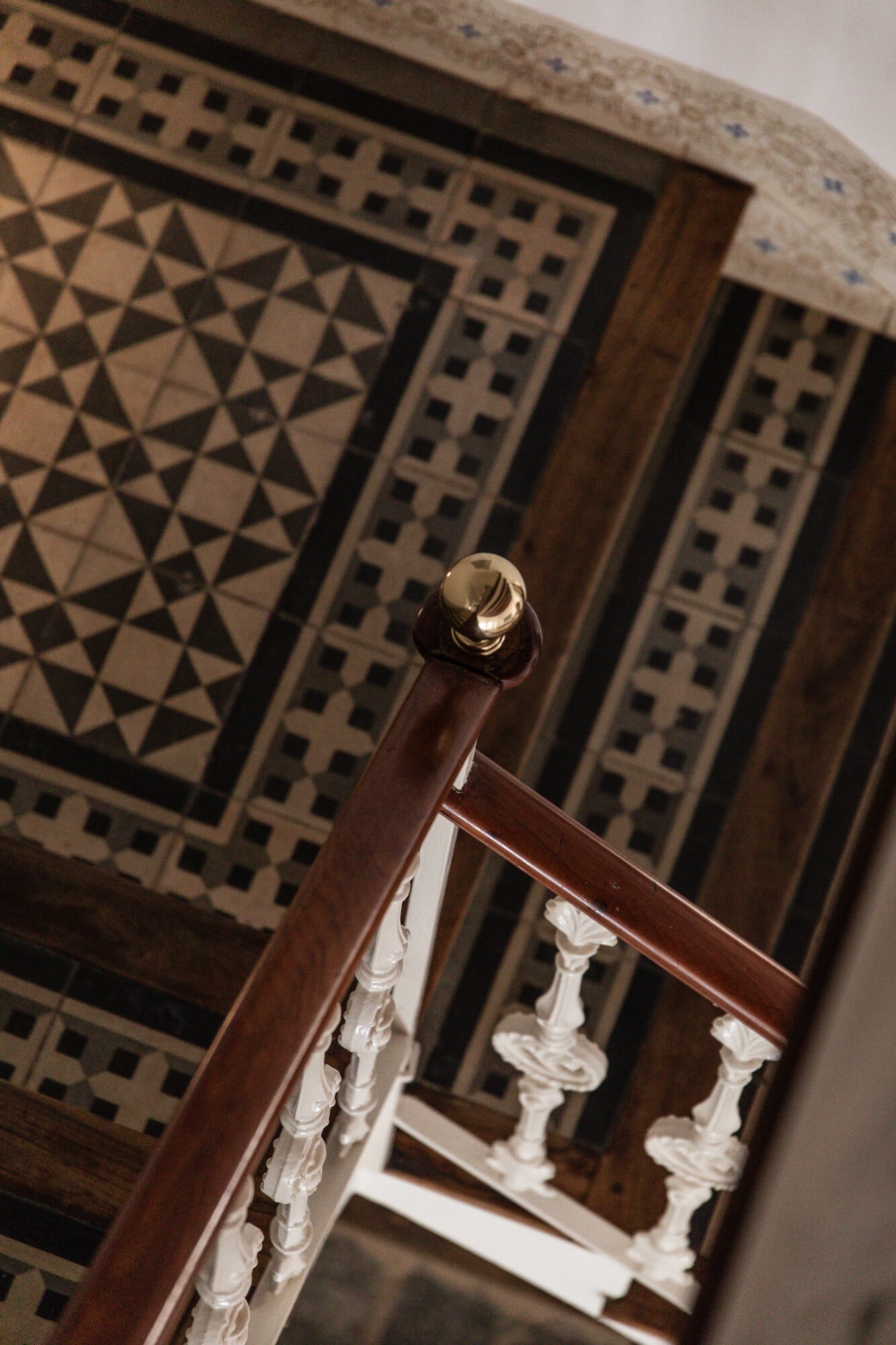 Mon Cor, Balearic Islands — Brass finial detail on wooden stair rail with geometric inlay and white carved balusters, luxury interior architecture.