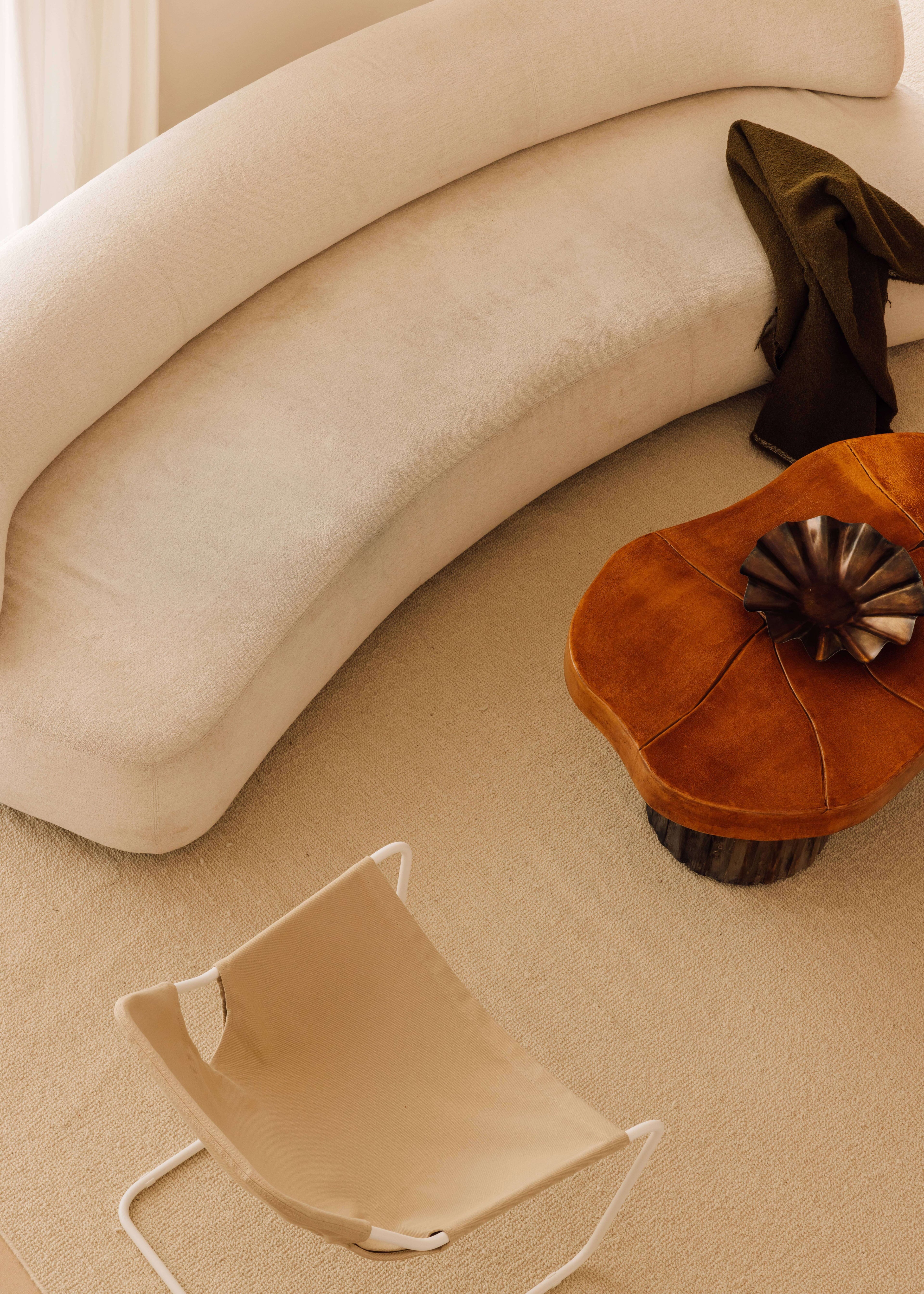 Casa Quatro, Europe — Curved cream upholstered furniture, cognac leather poufs, and neutral linen flooring in minimalist luxury interior.