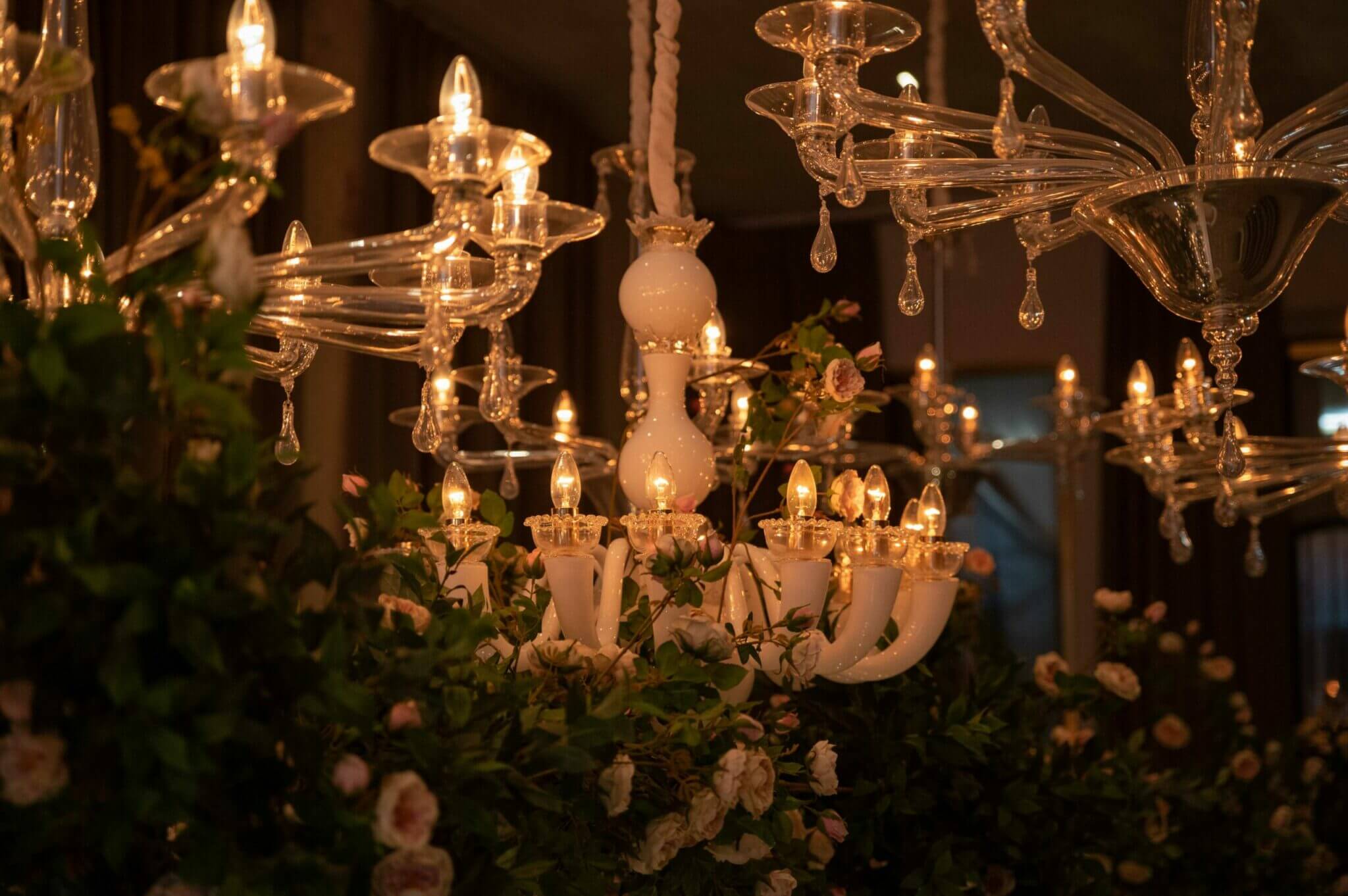 The Venice Venice Hotel, Europe — Crystal chandeliers with porcelain candle holders and cascading glass beads adorned with climbing roses, warm candlelit ambiance.