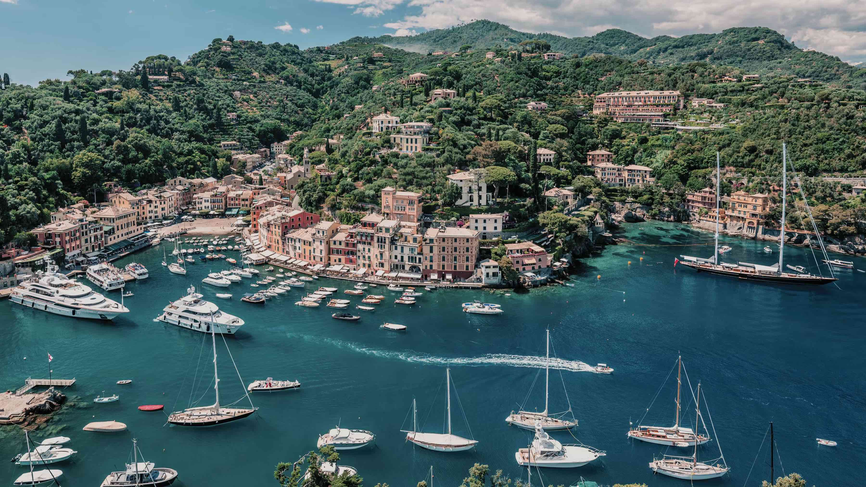 Splendido Mare, Portofino, Italy — Pastel-hued waterfront village nestled in forested hills with moored sailboats in crystalline turquoise bay.